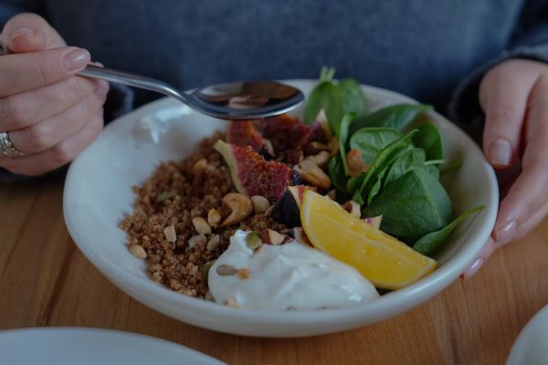 A vibrant brunch bowl with fruit, greens, and nuts for a nutritious meal.