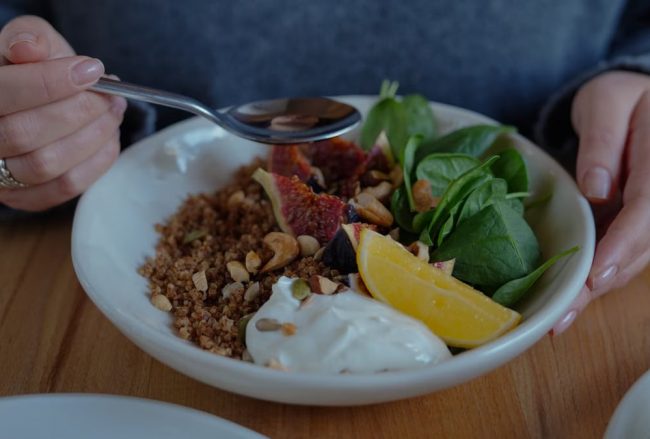 A vibrant brunch bowl with fruit, greens, and nuts for a nutritious meal.